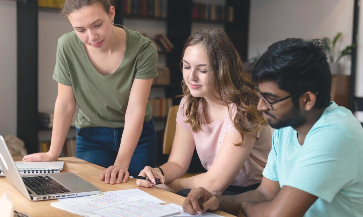 Groupe d'étudiants collaborant sur des projets financiers dans un environnement d'apprentissage moderne